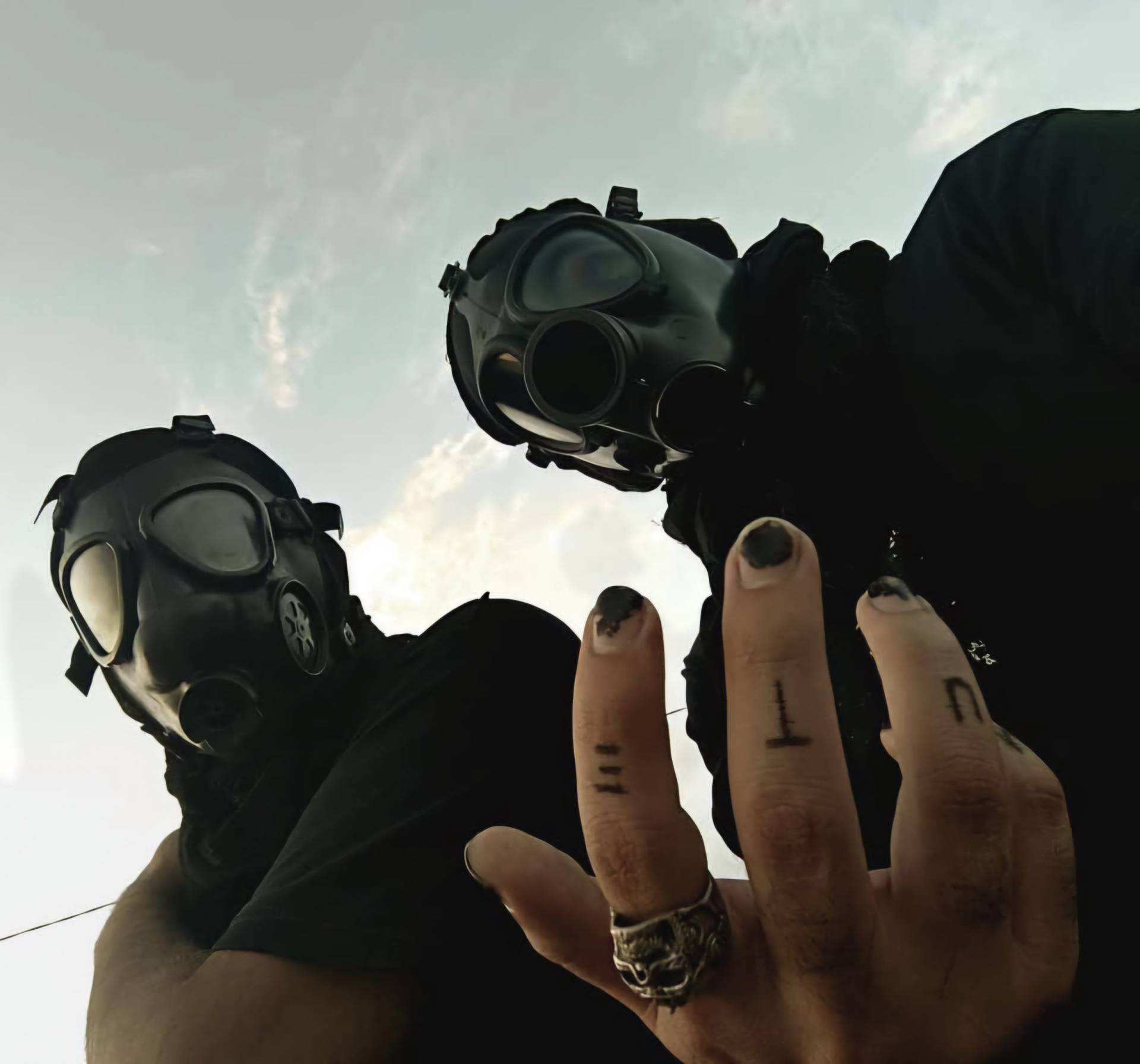 Two masked members of Wayloun stare down at the camera, with one hand in the foreground showing black nail polish, tattoos, and a skull ring.